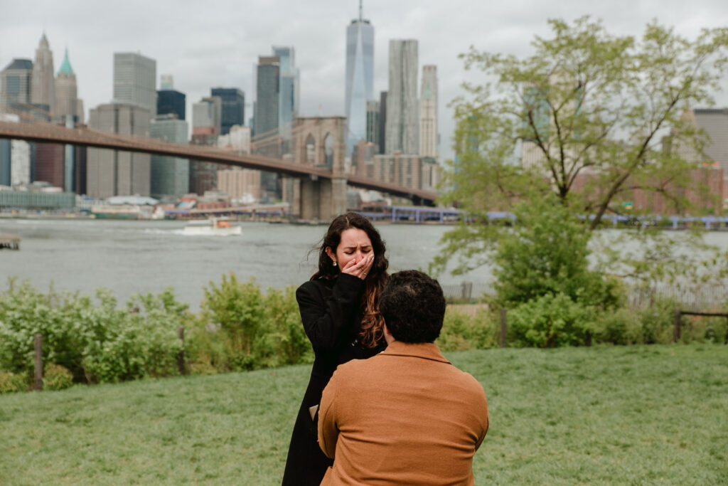 surprise proposal session at dumbo park with manhattan in the background
